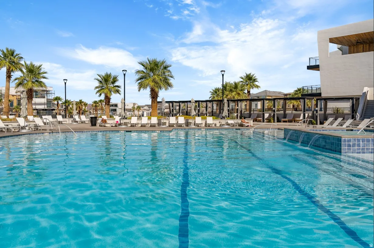Expansive outdoor pool featuring a tiled waterline, multiple water features, and surrounding palm trees
