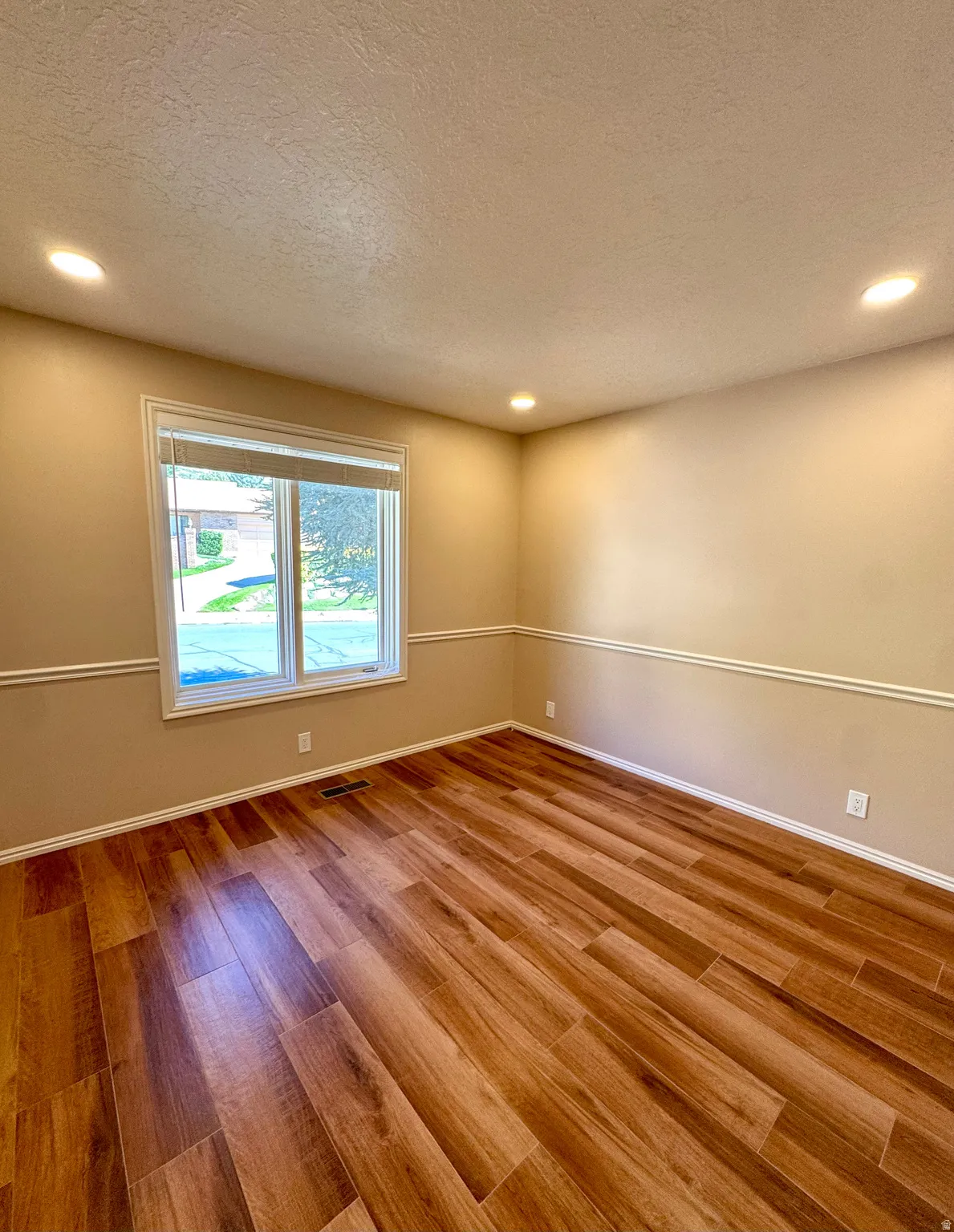 Recessed lighting illuminates wood-finish flooring
