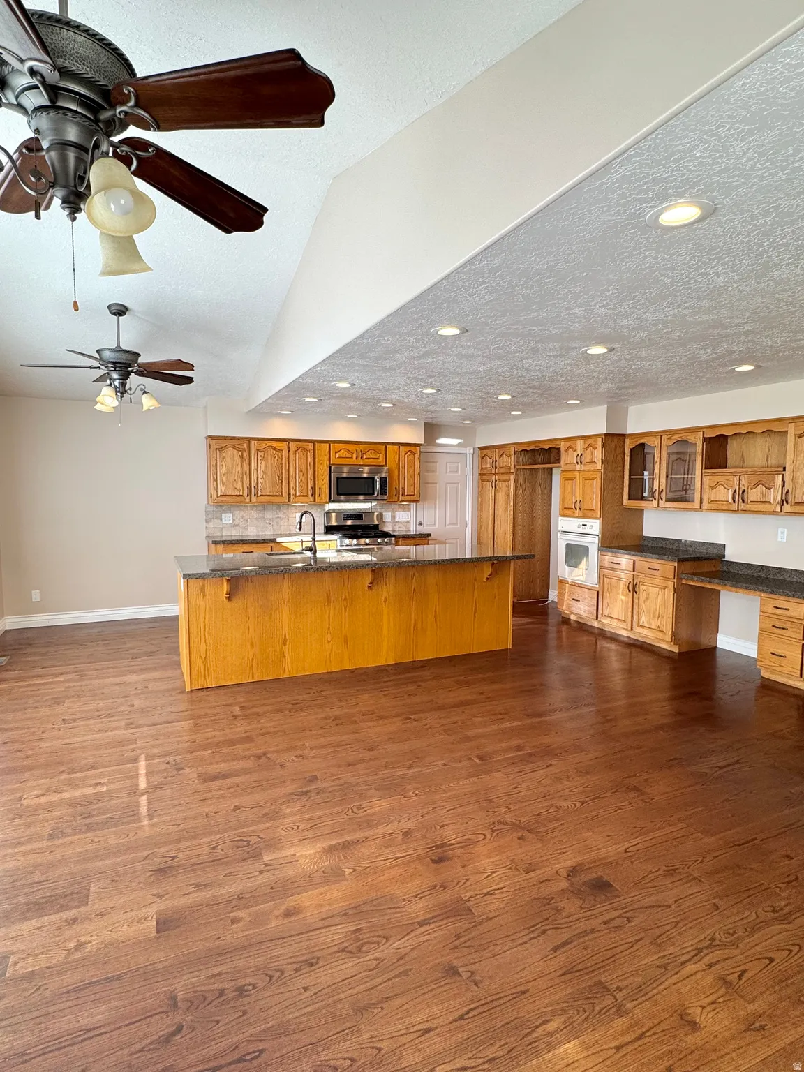 Spacious kitchen featuring a large island, wood-finish cabinetry, stainless steel appliances, and recessed lighting