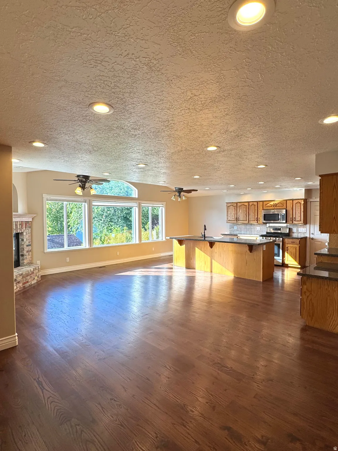 Open-concept living space featuring wood-finish flooring, recessed lighting, and large windows