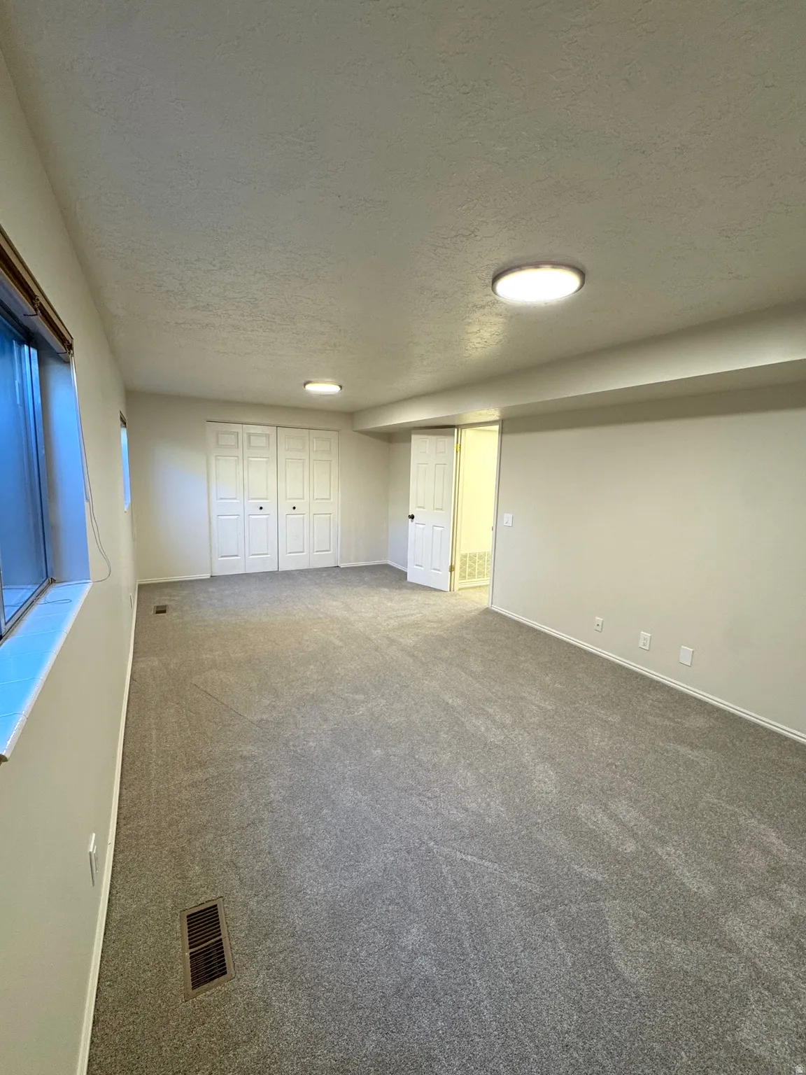 Carpeted room featuring dual bi-fold closet doors, white walls, and flush-mount ceiling lighting