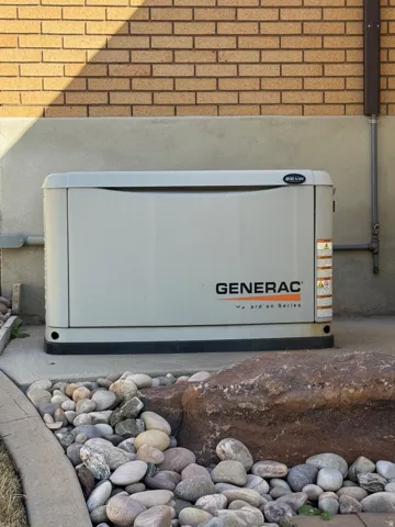 Generac standby generator on a concrete pad, complemented by a decorative rock bed