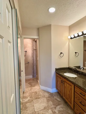 Vanity with a granite countertop, undermount sink, and wood-finish cabinetry