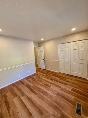 Wood-finish flooring, recessed lighting, neutral wall tones, and white trim