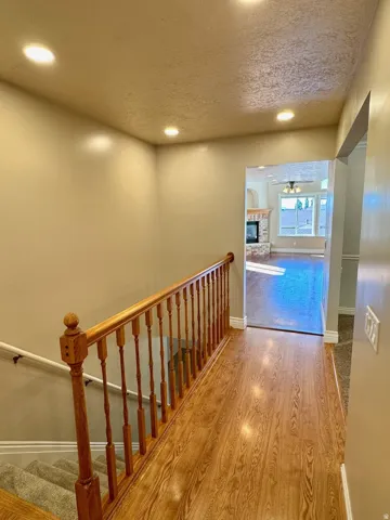 Wood-finish flooring with a wood spindle railing and recessed lighting
