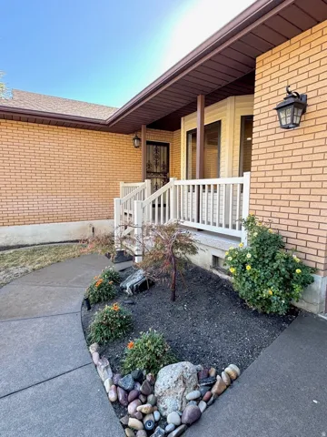 Brick exterior with white porch railing, bay window, landscaped rock garden, and concrete walkway