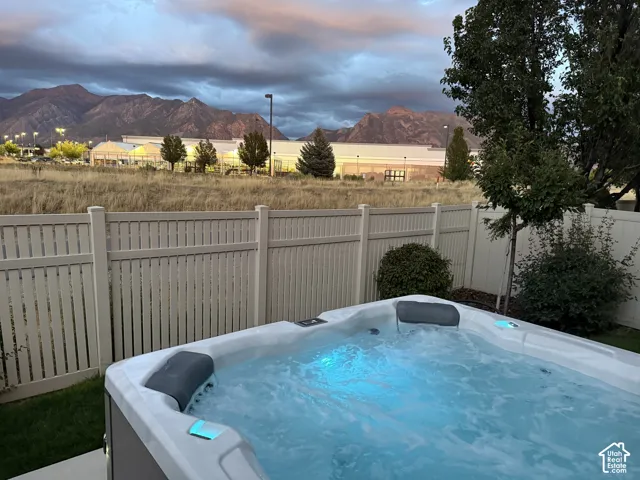 Backyard hot tub with integrated lighting, surrounded by a privacy fence and mature landscaping