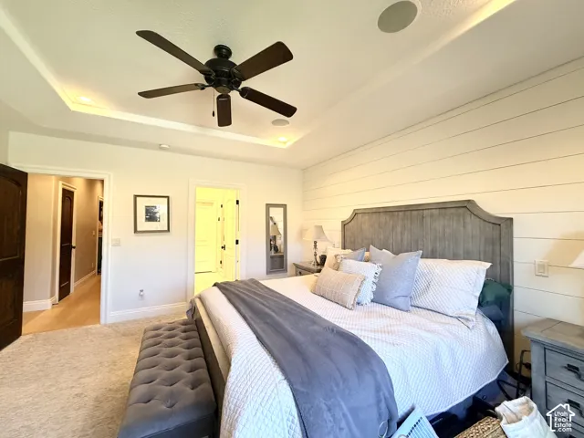 Tray ceiling with accent lighting, dark wood-finish ceiling fan, recessed lighting, shiplap accent wall, and light-colored carpeting