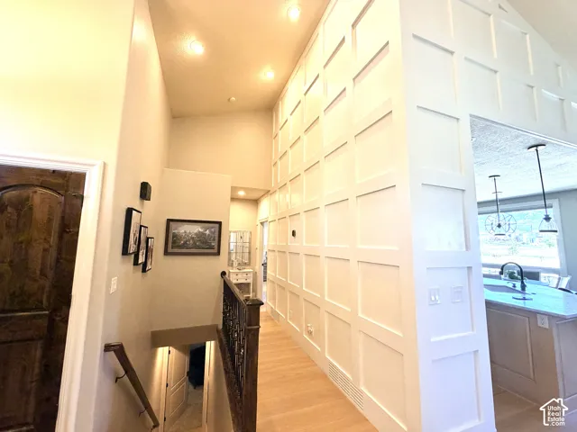 Vaulted ceiling with recessed lighting, laminate flooring, white panel accent wall, and a dark wood door