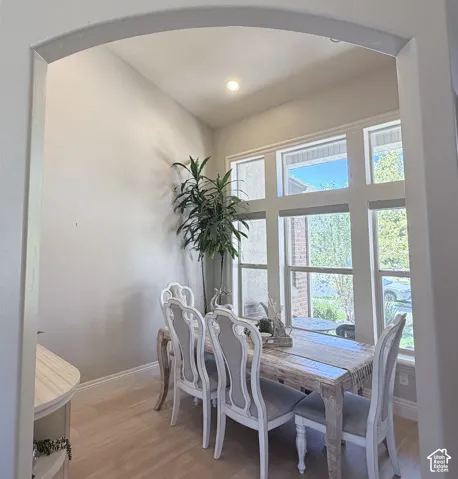 Arched entryway opening to a room with laminate flooring, vaulted ceilings, recessed lighting, and large multi-pane windows