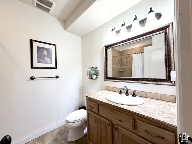 Wood-finish vanity with an oval basin sink, a neutral-toned countertop, and a vanity mirror with an ornate frame