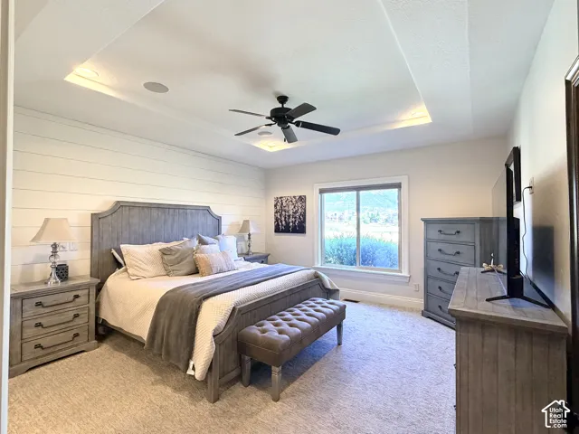 Tray ceiling with recessed lighting and a ceiling fan, accent wall with shiplap-style paneling, and wall-to-wall carpeting
