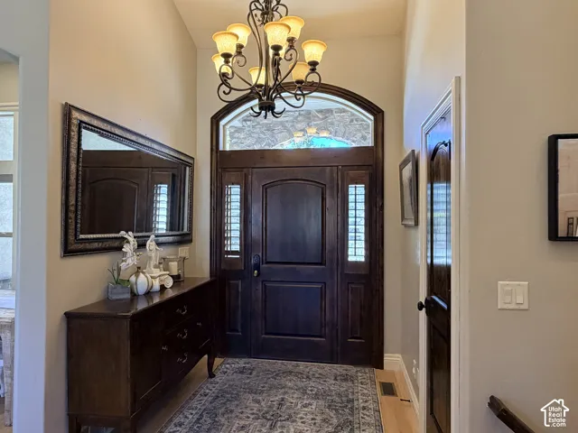 Grand entryway featuring a dark wood door with sidelights, an arched transom window, and a wrought iron chandelier