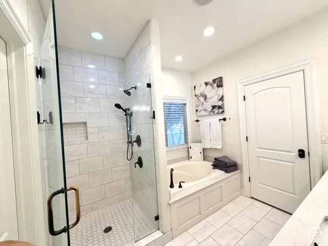 Glass-enclosed shower with subway tile walls and a hexagonal tile floor, soaking tub, window with blinds, and recessed lighting