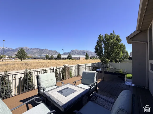 Expansive composite deck with a hot tub, bordered by a wrought iron fence with mature shrubbery