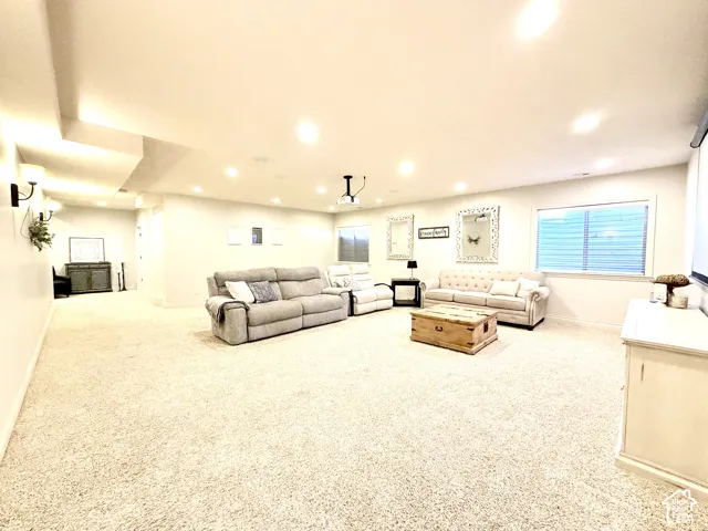 Expansive carpeted room featuring recessed lighting, a large window with blinds, and built-in ceiling speakers