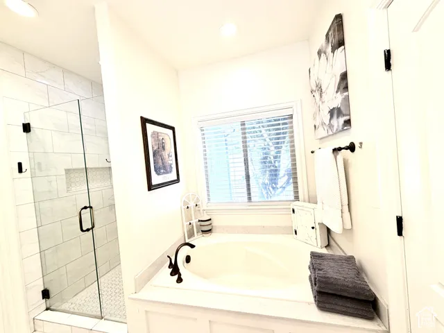 Built-in soaking tub with deck surround, walk-in shower with glass enclosure, tiled shower walls, recessed shower niche, and ceiling-mounted lighting