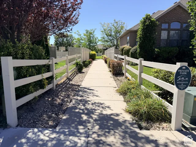 Concrete pathway bordered by white fencing and manicured landscaping