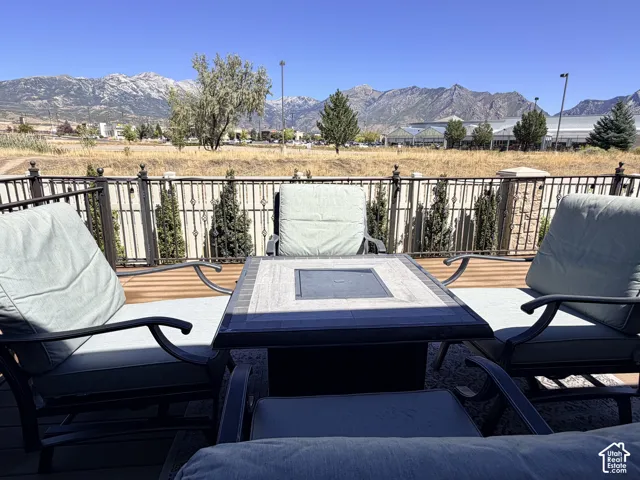 Expansive deck with wood-finish flooring, black metal railings, and a tiled fire pit table