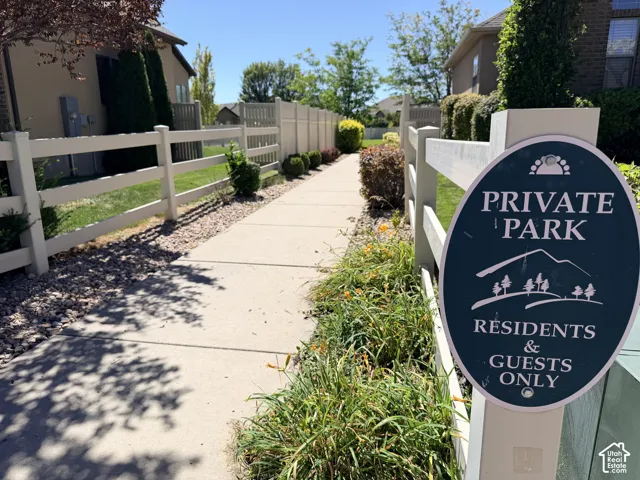 Paved pathway alongside a white split-rail fence, bordered by manicured landscaping
