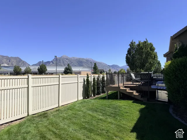 Manicured lawn with a privacy fence, multi-level composite deck, and mature landscaping