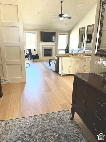 Vaulted ceiling with recessed lighting and ceiling fan, fireplace with tile surround and mantel, and built-in cabinetry