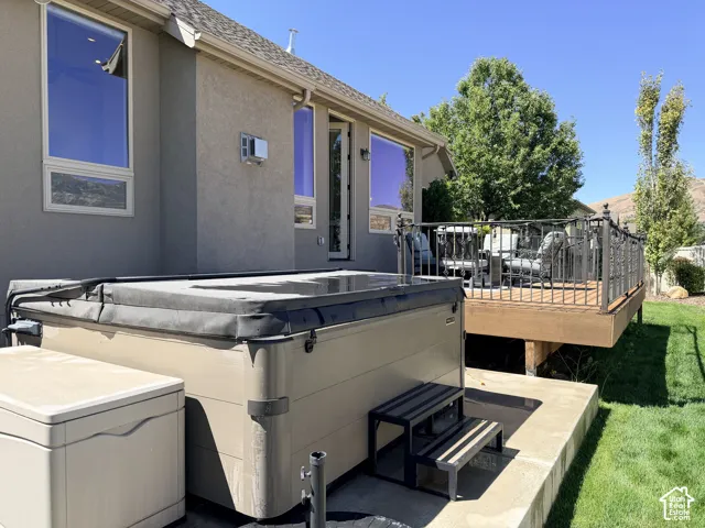 Outdoor spa, composite decking, wrought iron railing, stucco exterior, and dual-pane windows