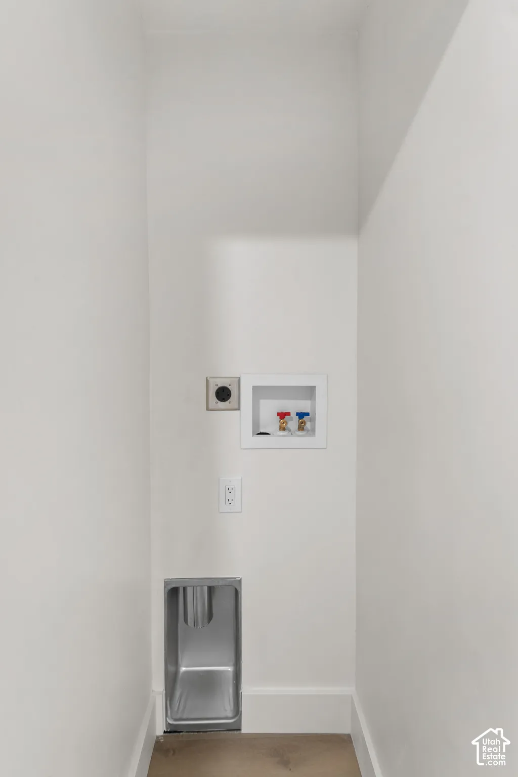 Laundry area with a stainless steel utility sink, electrical outlet, and washer hookups