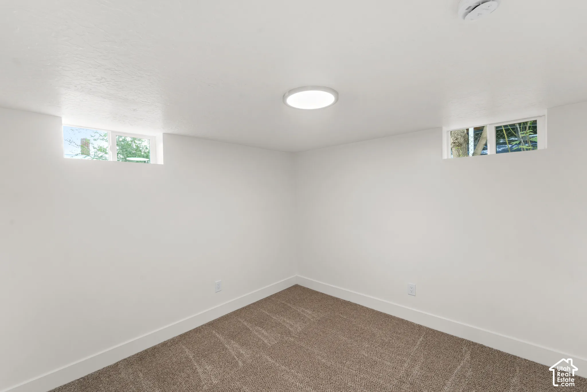 Neutral wall color, recessed windows, ceiling-mounted light fixture, and patterned carpeting