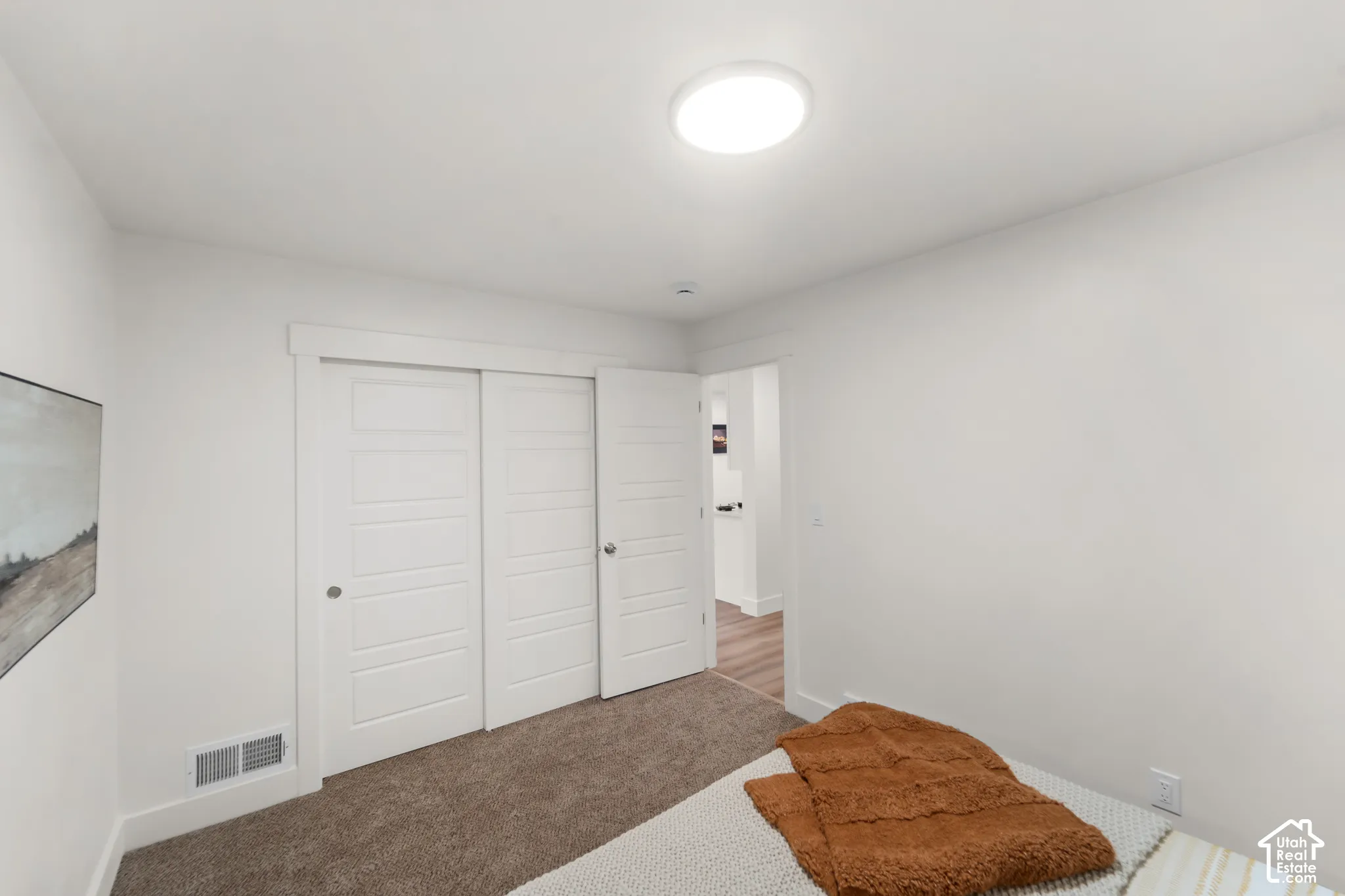 Neutral-toned wall-to-wall carpeting, white interior walls, white trim, recessed lighting, and a white interior door with contemporary hardware
