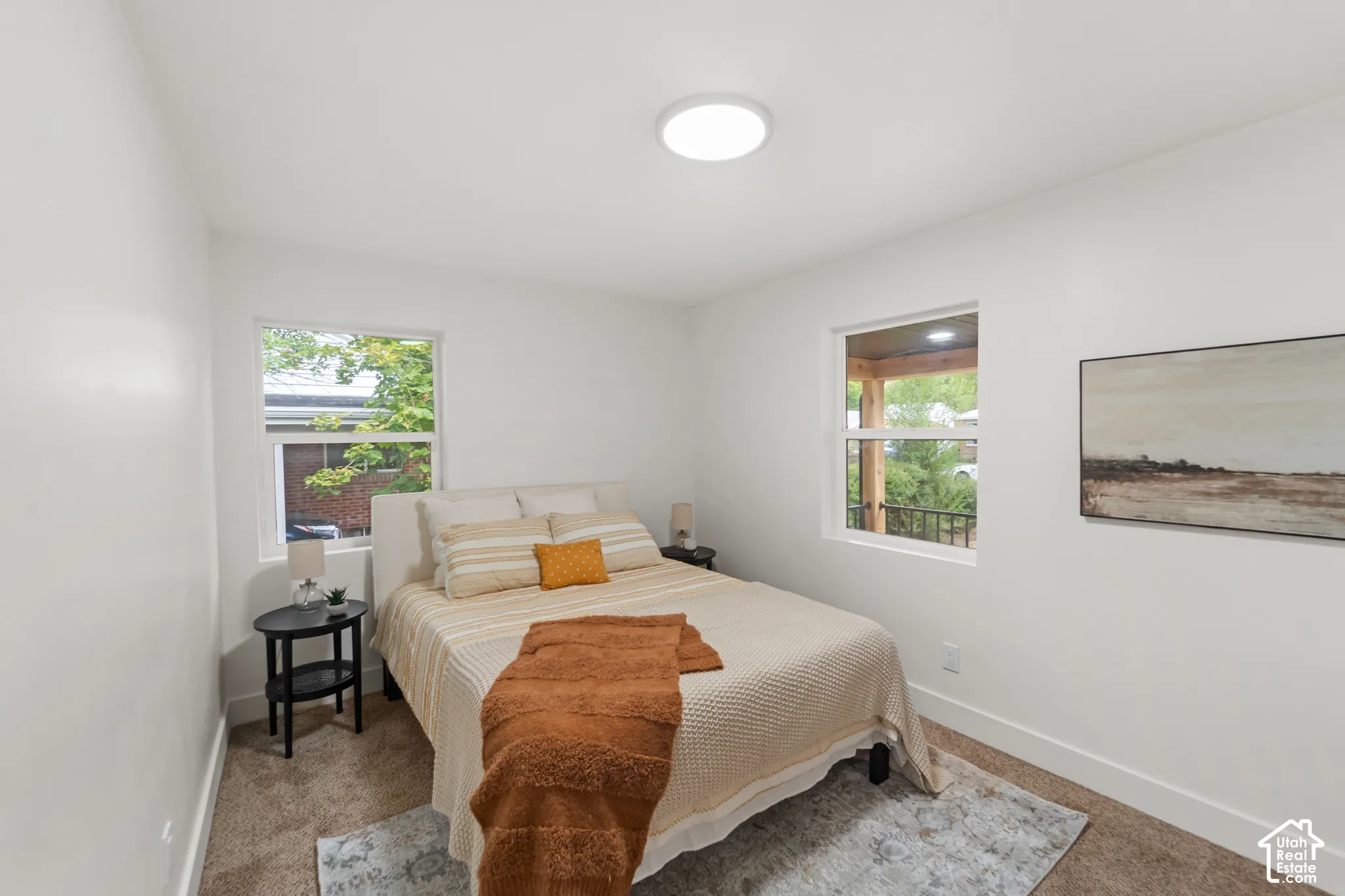 White walls, neutral carpet, and two windows with white trim