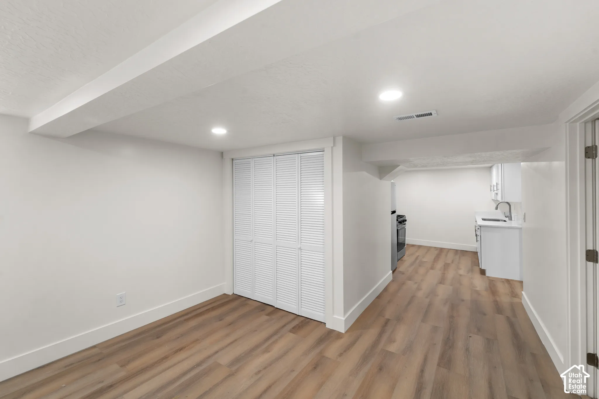 Wood-finish flooring, recessed lighting, and white louvered closet doors