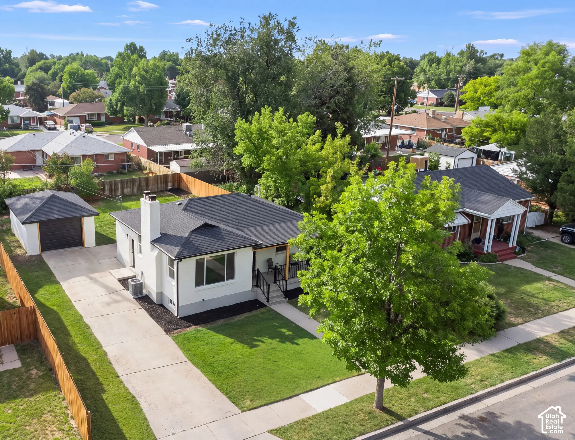 Detached garage with dark panel door, concrete driveway, and front lawn