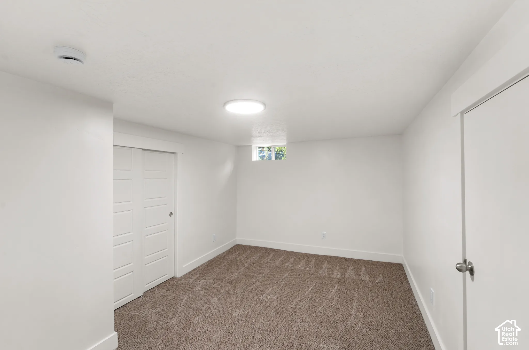 Carpeted flooring, white walls, built-in closet with bi-fold doors, recessed ceiling lighting, and a single window