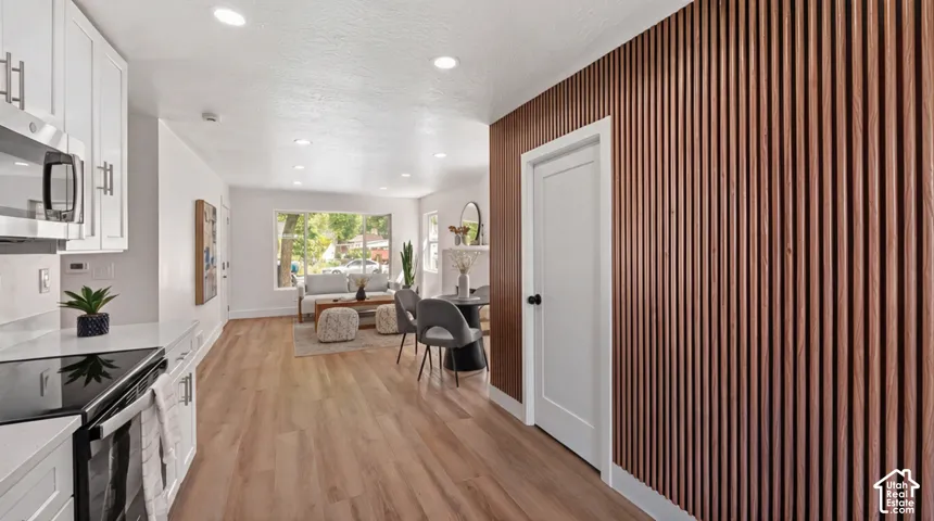 White shaker cabinetry, light wood-finish flooring, recessed lighting, and a slatted accent wall
