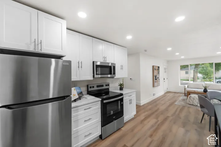 Kitchen featuring stainless steel appliances, white cabinetry with silver-tone hardware, and light-toned countertops