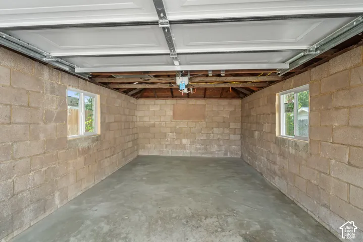 Concrete block walls, two windows, exposed wood beams, and a concrete floor