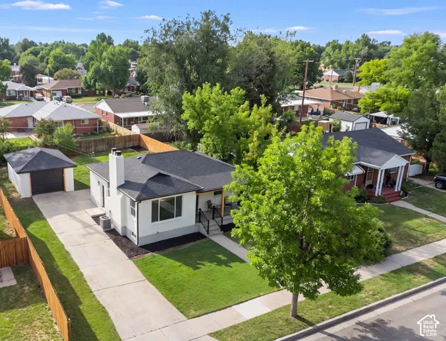 Detached garage with dark panel door, concrete driveway, and front lawn
