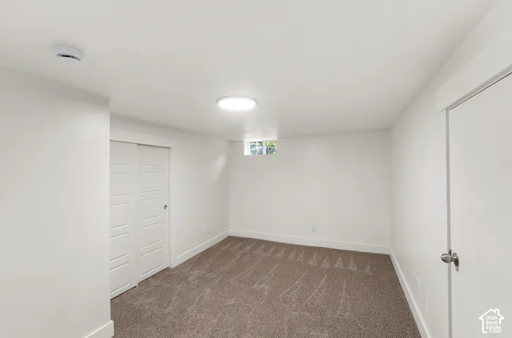 Carpeted flooring, white walls, built-in closet with bi-fold doors, recessed ceiling lighting, and a single window