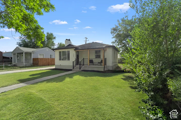 Single-story residence with a covered porch, front yard, concrete walkway, and established trees
