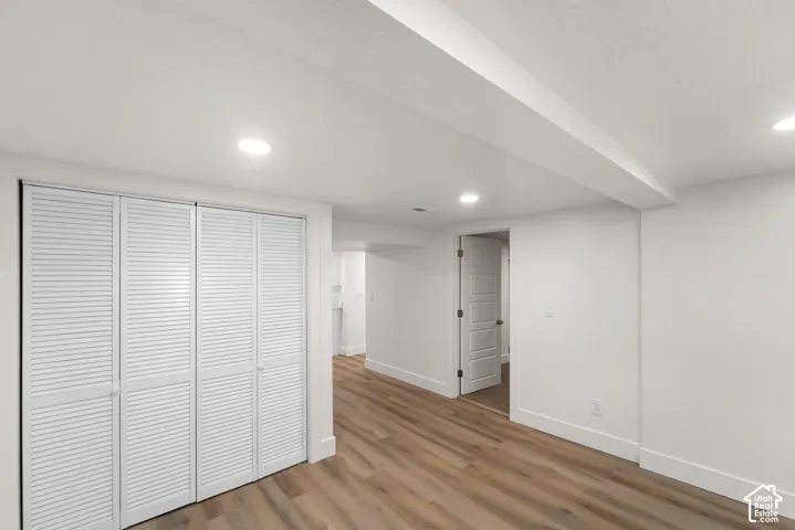 White louvered bifold closet doors, recessed lighting, wood-finish flooring, and white interior doors