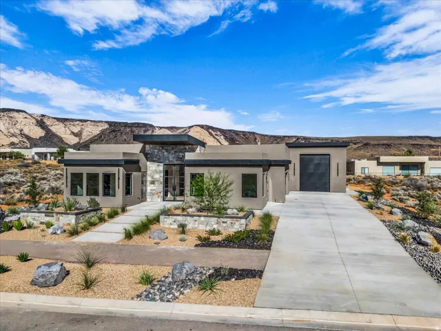 Modern facade with stone accents, integrated garage, concrete driveway, and desert-inspired landscaping