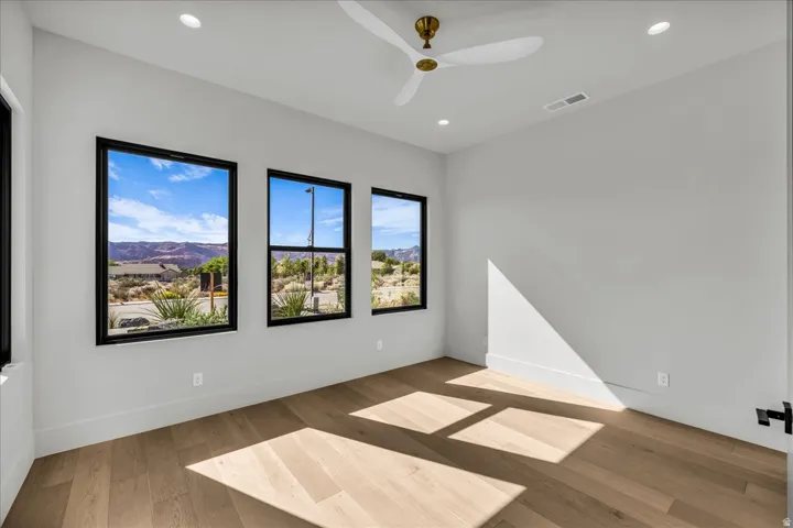 Recessed lighting, wood-finish flooring, white walls, and a ceiling fan with brass accents