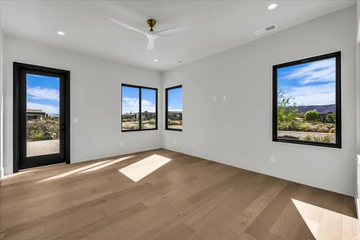 Light wood-finish flooring with recessed lighting and a ceiling fan