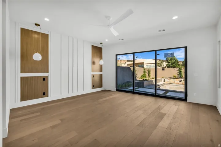 Spacious interior showcasing wide-plank wood-finish flooring, white shiplap wall paneling, and recessed ceiling lighting