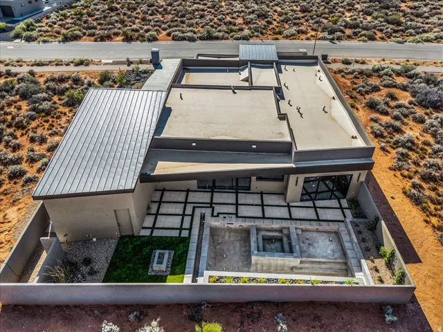 Modern exterior with a combination flat and standing seam metal roof, geometric patio with integrated turf, and an in-ground pool and spa