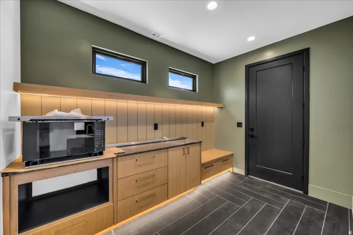 Built-in cabinetry with wood-finish drawers, under-cabinet lighting, dark panel door, and recessed lighting