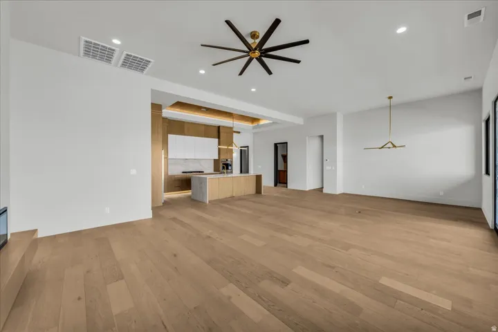 Open-concept living space with wood-finish flooring, a contemporary ceiling fan, recessed lighting, and a modern linear chandelier