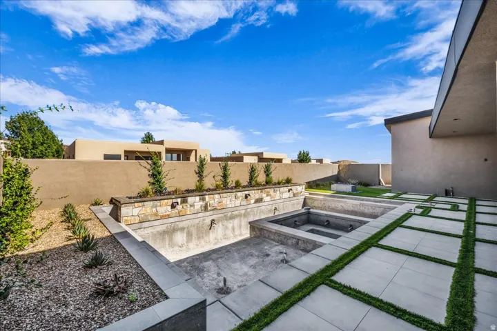 Expansive outdoor living area featuring a pool, integrated spa, and contemporary hardscaping with grass accents