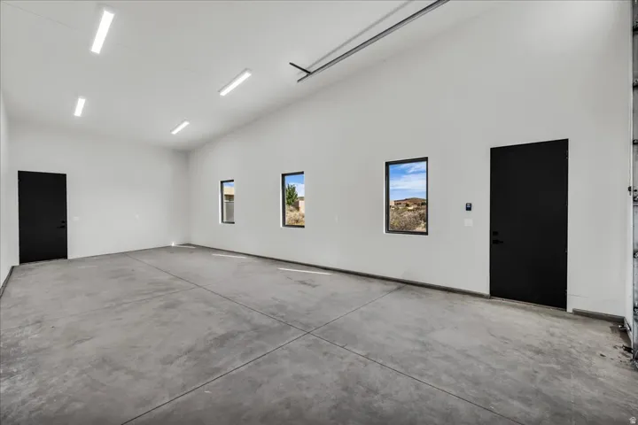 Spacious garage featuring a concrete floor, multiple windows, and two entry doors
